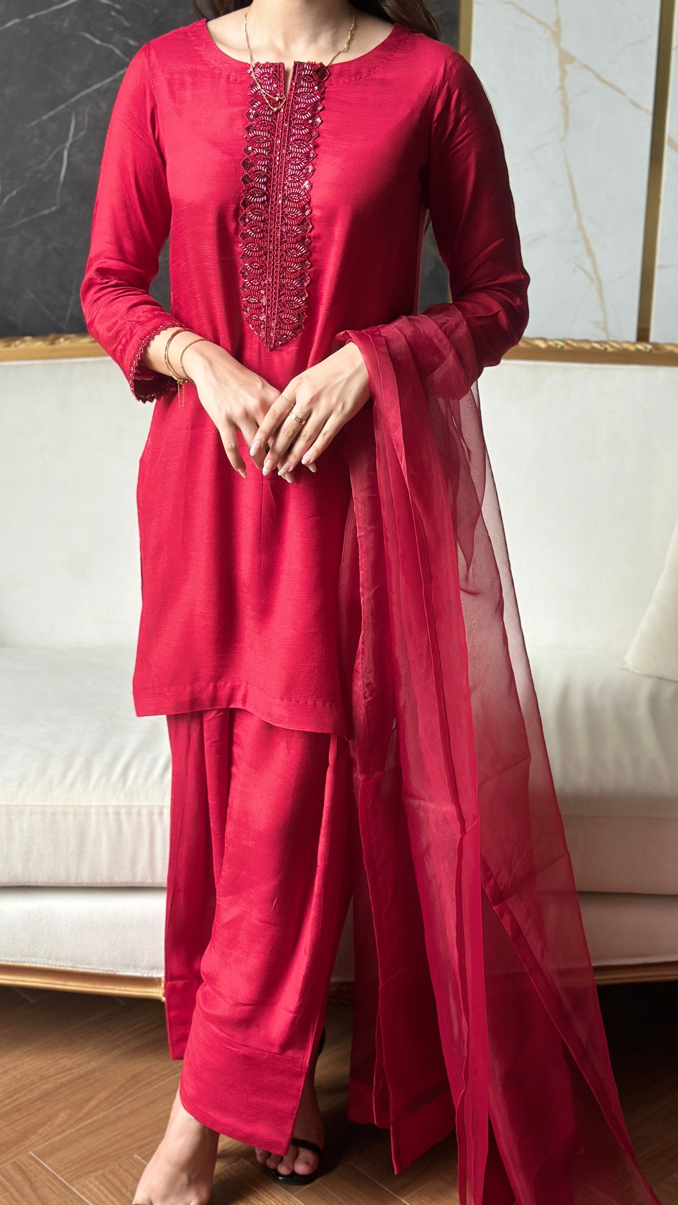 Red traditional outfit with intricate detailing on a neutral background
